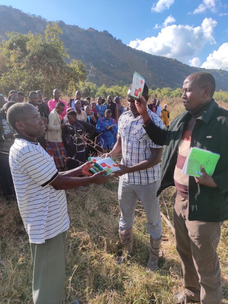 Training in Tanzania, three men are sharing materials