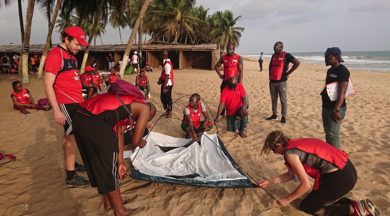 People blindfolded to build a tent on the beach as a teambuilding exercise