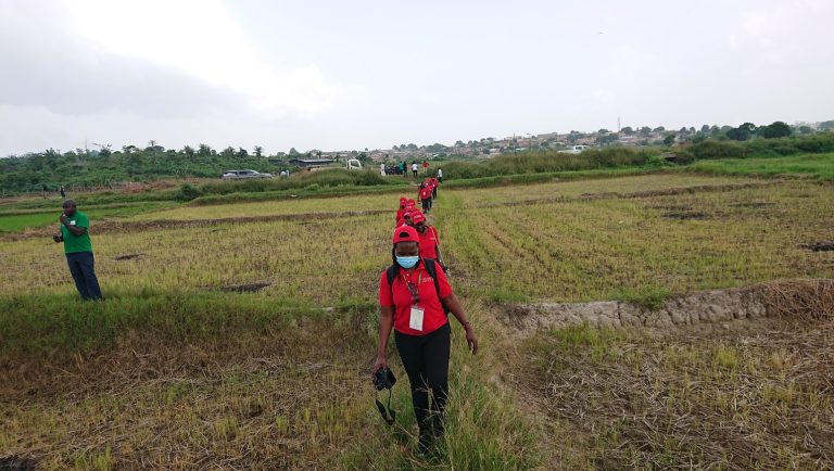 2SCALE people walking in a line through a field wearing matching red shirts